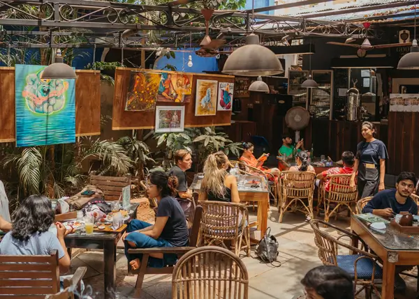 A crowded Artjuna cafe with paintings on the board in Assagao North Goa